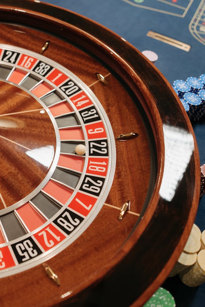 Close-up of a roulette wheel with poker chips in a casino setting, highlighting chance and gambling.